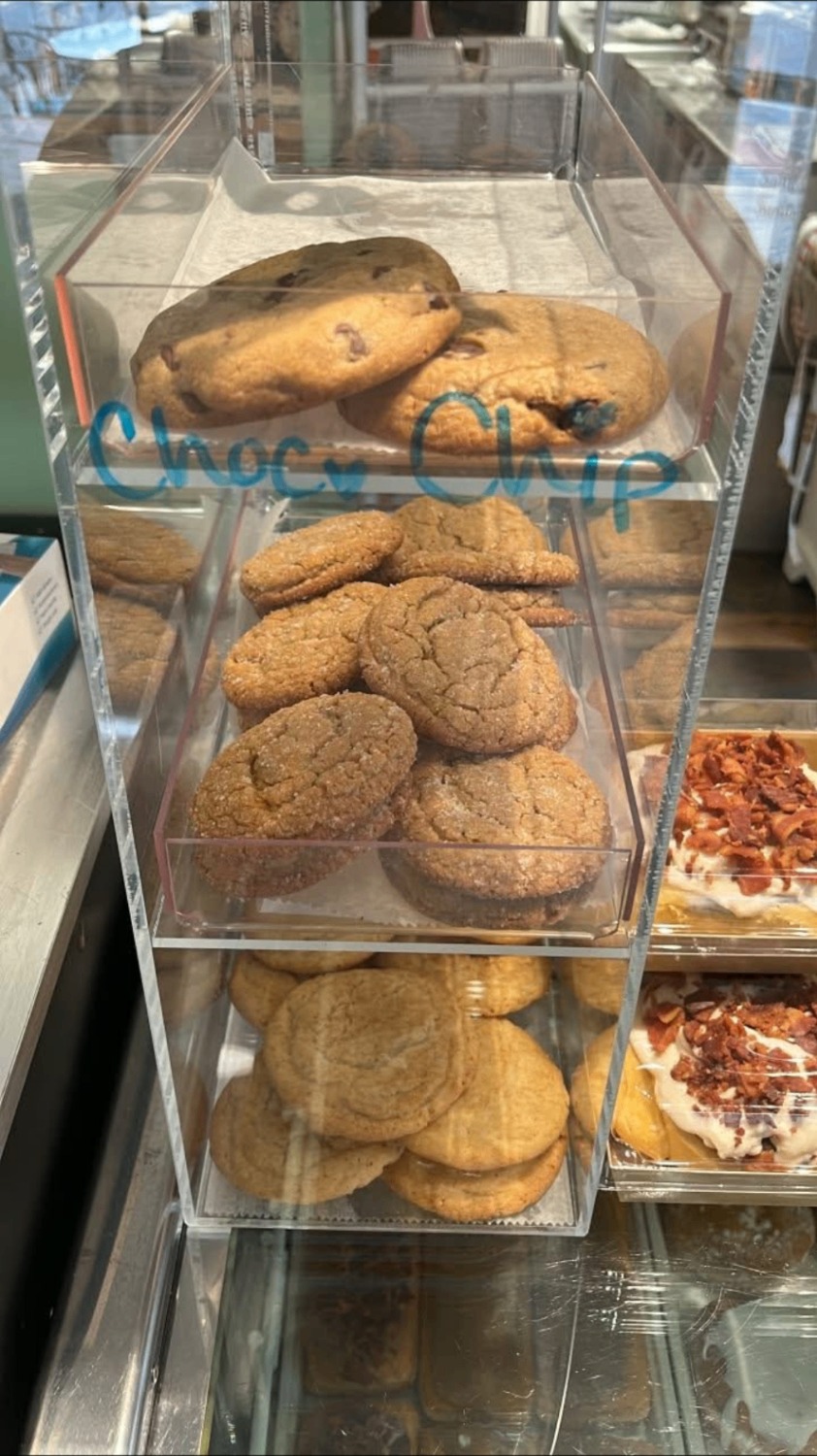 Chocolate chip, ginger and sugar cookies stacked in a clear bakery case