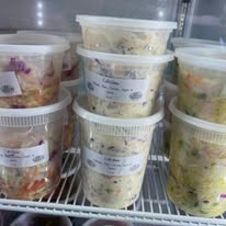 Containers of chicken salad with grapes and pecans on a cooler shelf