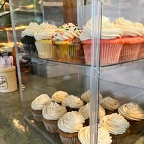 Cupcakes with tall swirls of vanilla buttercream in the bakery display case