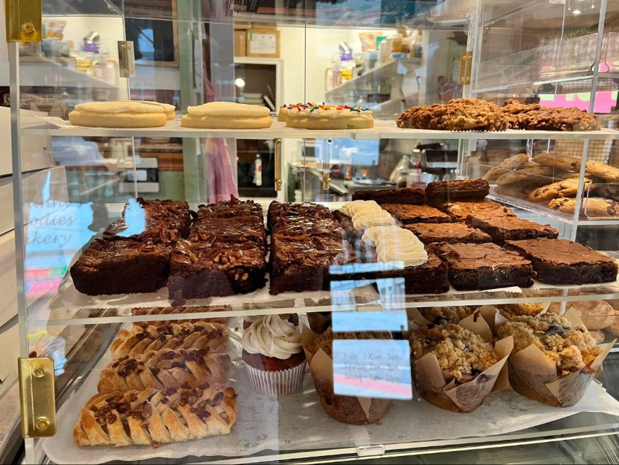Pecan brownies, muffins, cupcakes and pastries on shelves in the bakery case