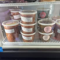 Containers of fresh salsa and cowboy candy in the refrigerated case